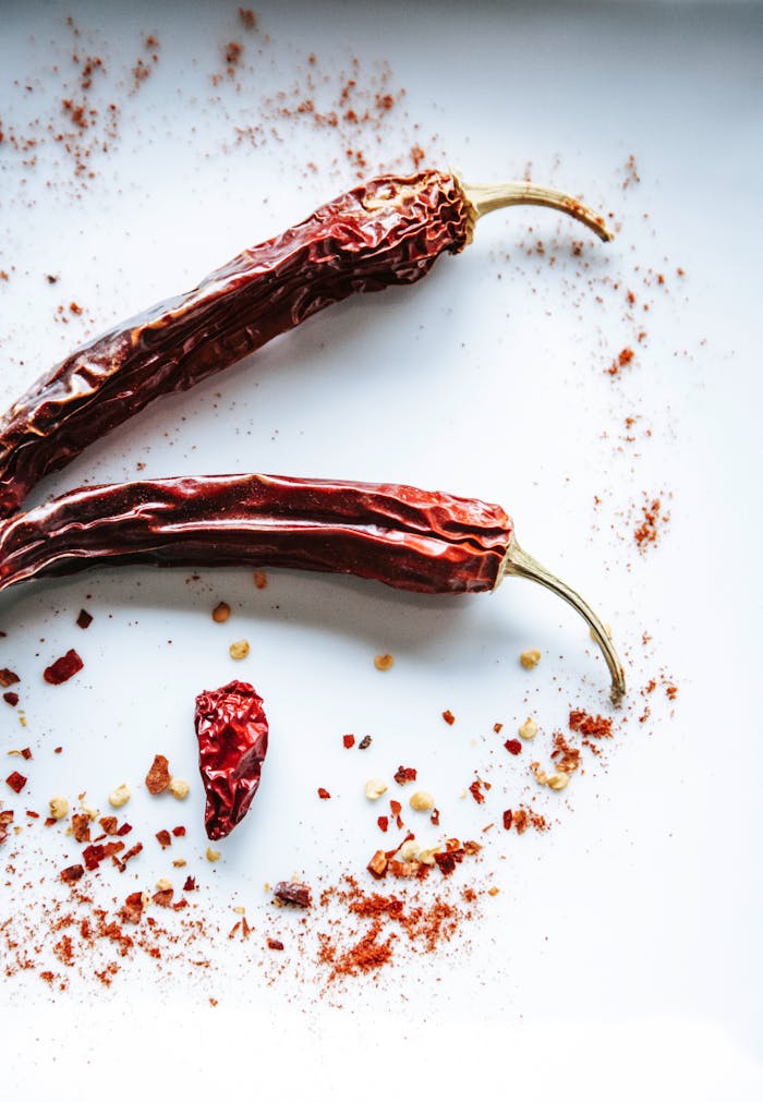 Vibrant image of dried chili peppers and spices on a white background, perfect for culinary projects.